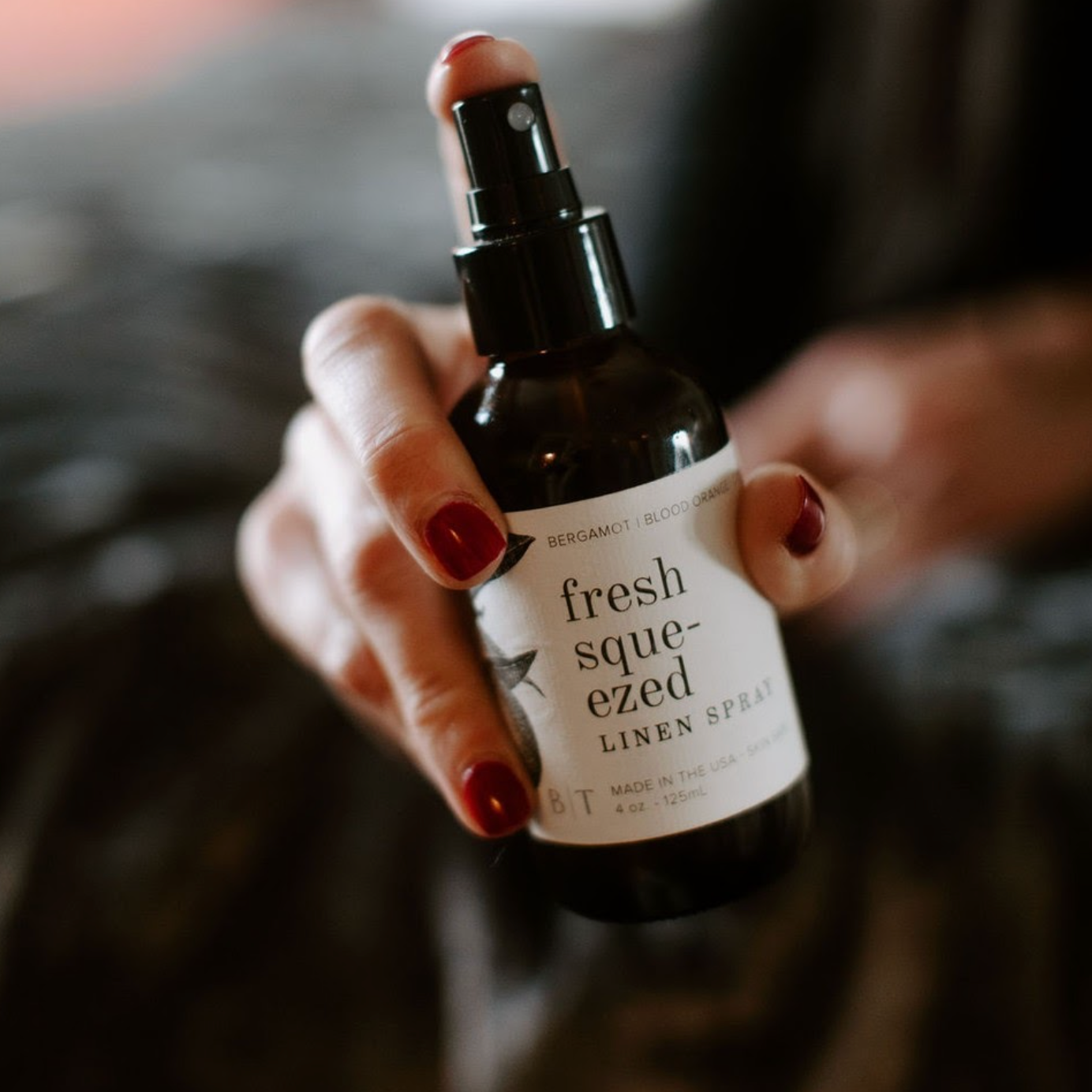 4oz Fresh Squeezed Linen Spray being sprayed by a woman's hand. 