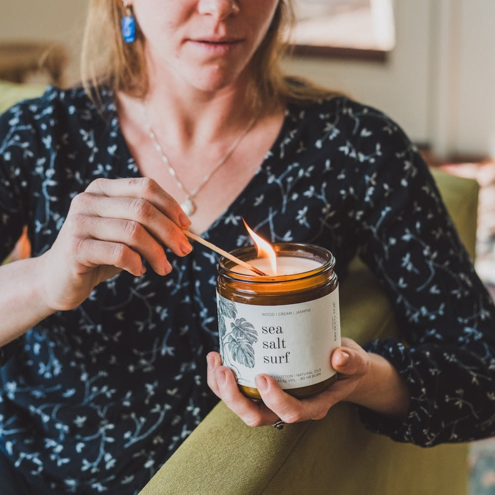 16oz Sea Salt Surf Soy Candle being lit by a match. 