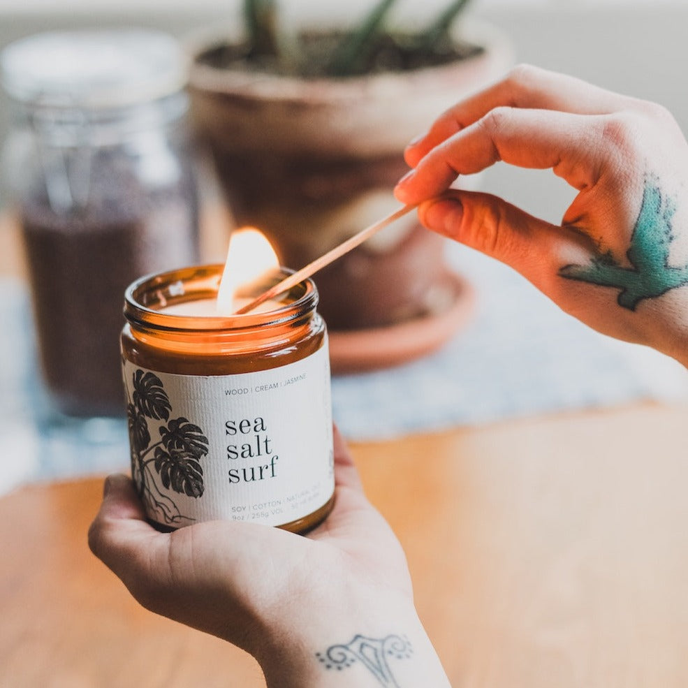 9oz Sea Salt Surf Soy Candle being lit by a match. 