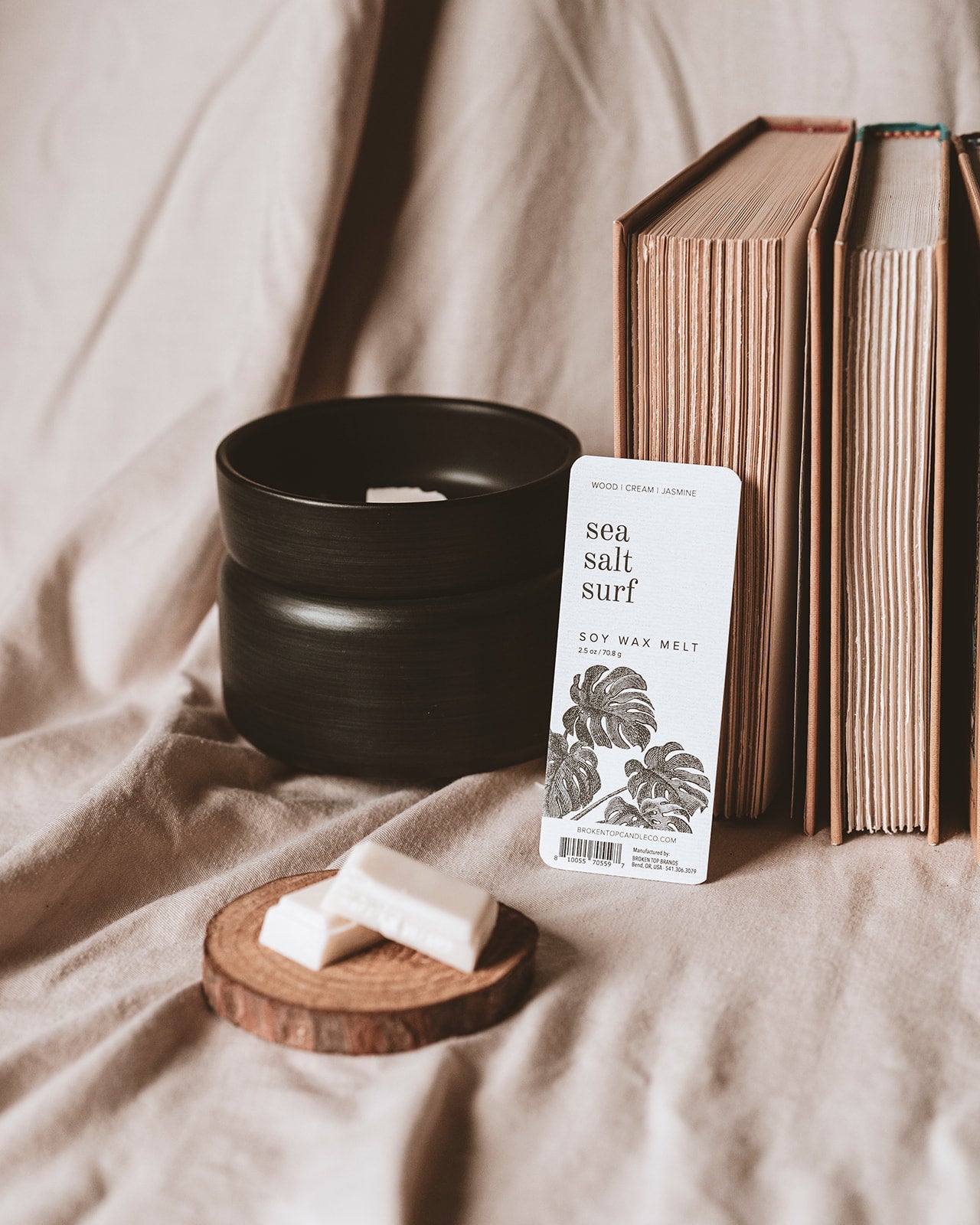 Sea Salt Surf Wax Melts in a black wax melter next to books. 