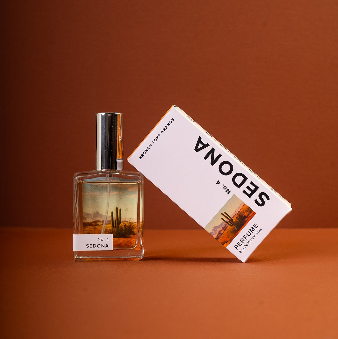 Sedona Perfume bottle and box on a dark orange background. 