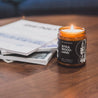 9oz Sitka Woodland Soy Candle on a coffee table next to a stack of magazines. 