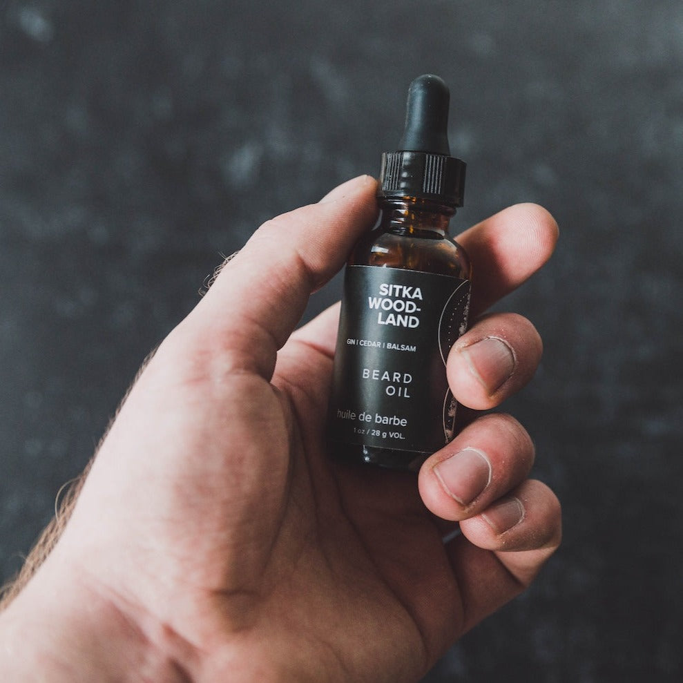 1oz Sitka Woodland Beard Oil being held by a hand. 