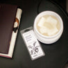 Spiced Winter Plum Soy Wax Melt on black side table next to a white wax melter and stack of books. 