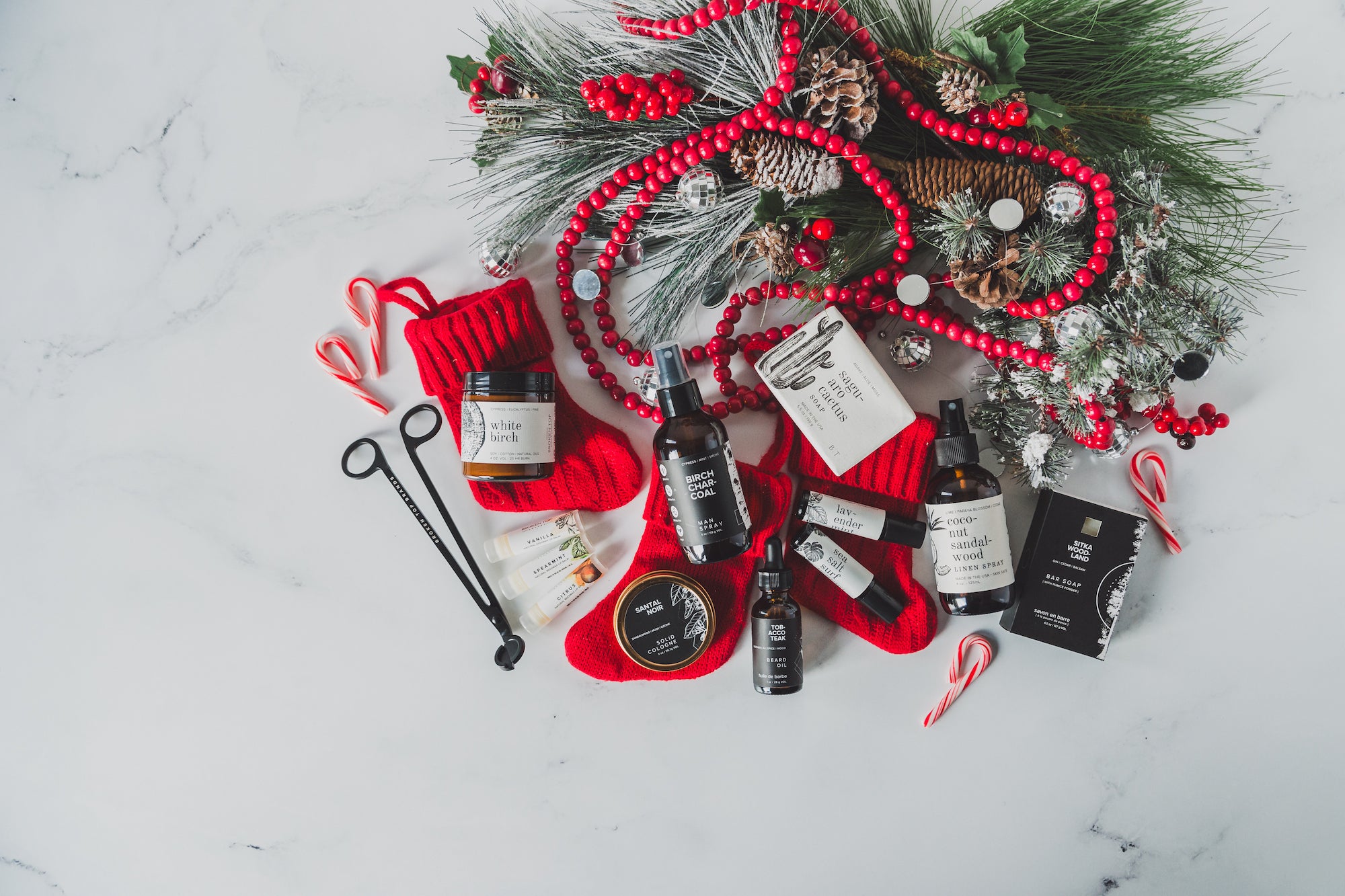 An array of products by Broken Top Brands laid out atop red Christmas stockings and other Christmas decor. 