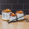 Broken Top Brands Black Wick trimmer in front of three Broken Top Soy Candles. 
