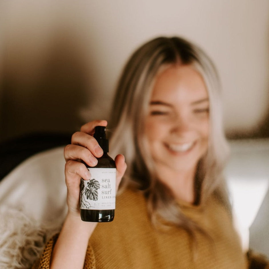 4oz Sea Salt Surf Linen Spray being sprayed by a woman. 