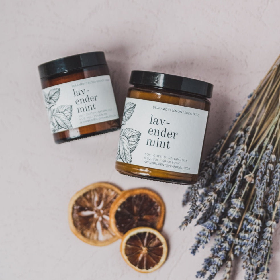 9oz Lavender Mint Soy Candle next to dried lavender and citrus slices. 