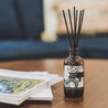 Apricot Bloom Reed Diffuser on coffee table next to magazines. 