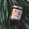 9oz Mango Paprika Soy Candle on leafy green background. 