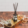 Fresh Squeezed Reed Diffuser on a gold tray next to decorative orange slices. 
