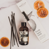 Fresh Squeezed Reed Diffuser on marble countertop next to decorative orange slices. 