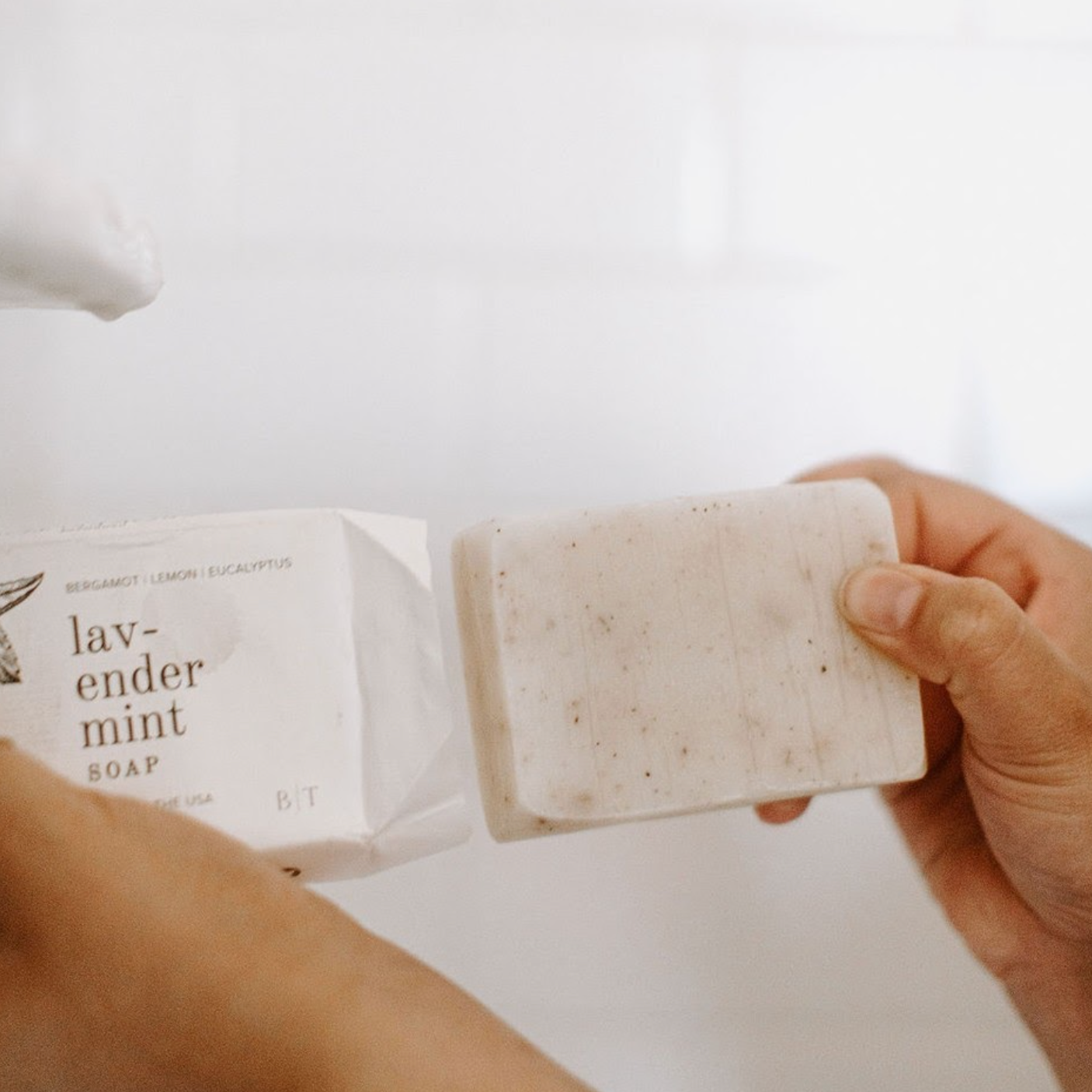 Lavender Mint Bar Soap being unwrapped by two hands. 