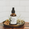 4oz Citrus Herbed Tonic Linen Spray on small metal tray. 