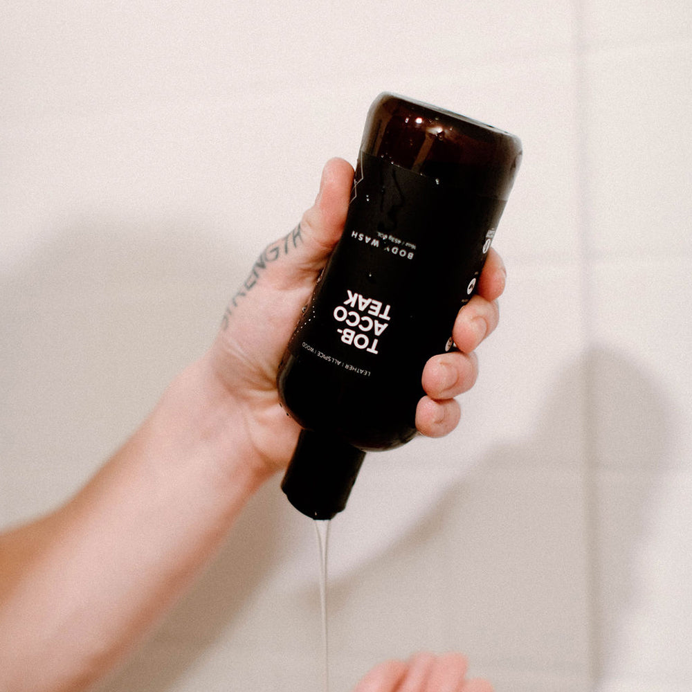 16oz Tobacco Teak Body Wash being squeezed into a hand. 