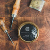 Tobacco Teak Solid Cologne on wooden table next to hand tools and a flask. 